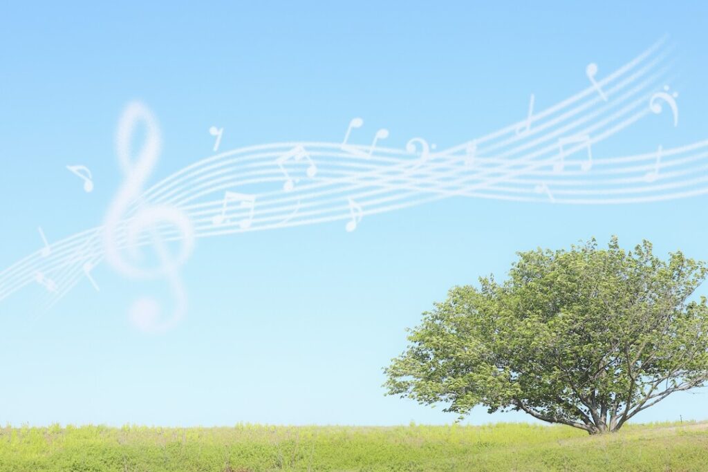 青空が広がる自然の中に音楽が流れている様子