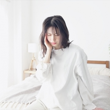 耳に手を当て辛そうな表情の女性の写真