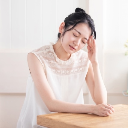 こめかみを抑えて辛そうな女性の写真